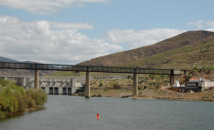 Steel (or iron) truss bridge across the the Douro River near a hydroelectric dam with locks for ships
