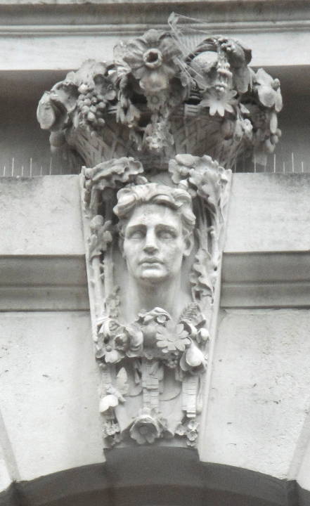 Keystone with man with curly hair surrounded” by flowers