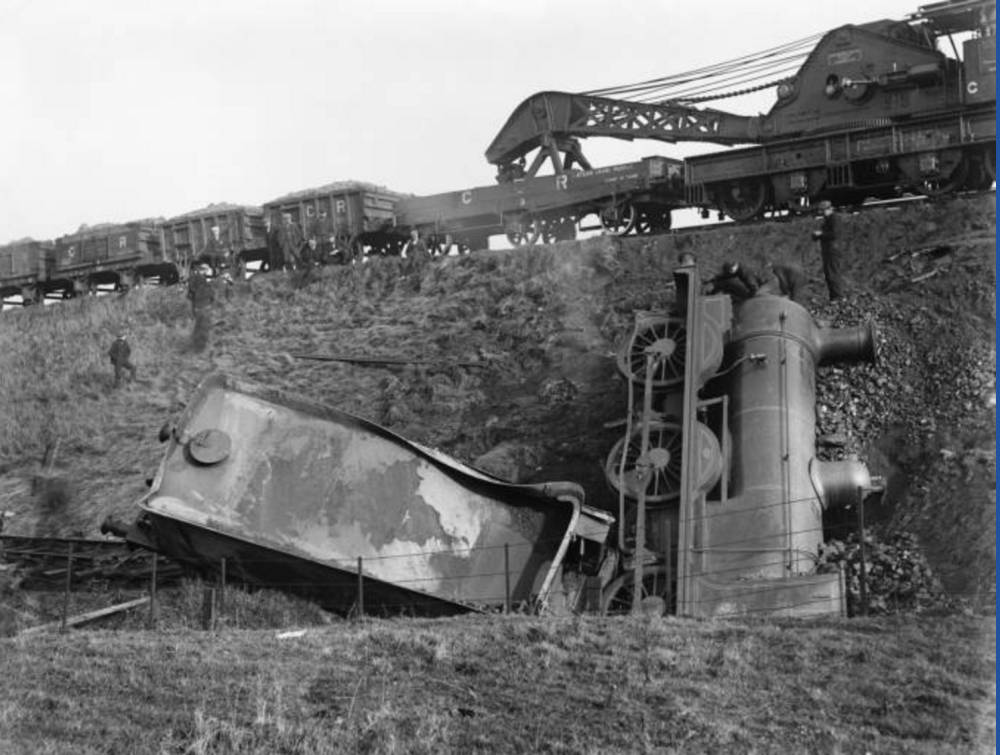 Railway disaster: locomotive and tender  with breakdown crane on track above